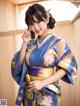 A woman in a blue and yellow kimono posing for a picture.