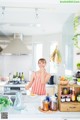 A woman standing in a kitchen holding a wooden spoon.