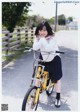 A young woman standing next to a yellow bike.