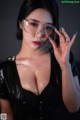 A woman in a black dress holding up a pair of glasses.