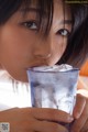 A woman holding a glass of water with ice in it.