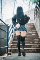 A woman in a skirt and sweater is walking up some stairs.