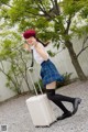 A woman in a school uniform with a suitcase.