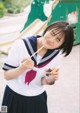 A woman in a school uniform holding a cup of ice cream.