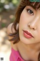 A close up of a woman's face with a pink dress.