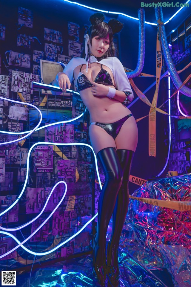 A woman in a bikini and thigh high boots posing for a picture.