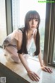 A woman in a pink dress leaning on a window sill.