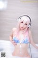 A woman in a bikini and headphones in a bathtub.