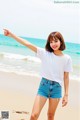 A woman standing on a beach pointing at the ocean.