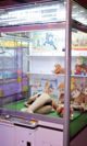 A woman laying on the floor in front of a display case filled with stuffed animals.