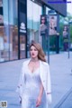 A woman in a white dress is walking down the street.