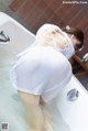 A woman in a white dress is taking a bath in a tub.