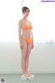 A woman in an orange bikini standing on a scale.